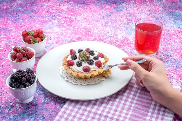 delicious creamy cake getting eat by female with different fresh berries juice on bright-light desk, berry fruit color fresh photo sour