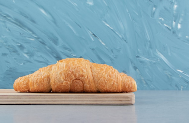 Free photo delicious croissant on the board , on the blue background . high quality photo