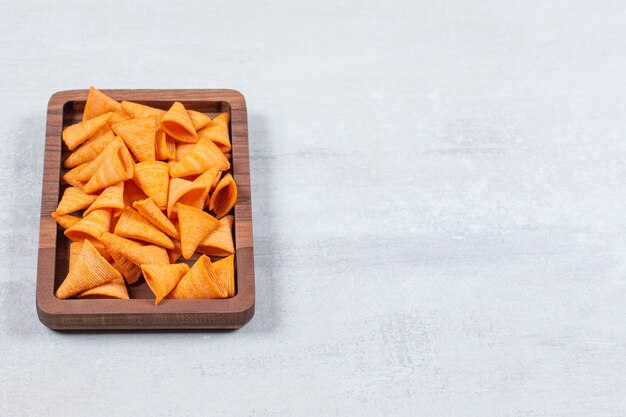 Delicious crunchy chips on wooden plate.