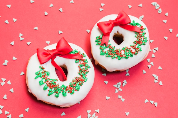 Free Photo delicious donut decorated for christmas on red backdrop with sprinkles