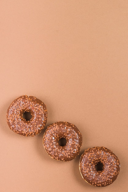 Free Photo delicious doughnuts with icing on brown background