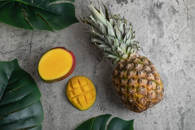 Delicious exotic mango fruit and pineapple on marble surface.