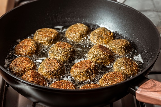 Delicious falafel frying in pan high angle