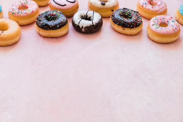 Delicious fresh donuts on pink backdrop