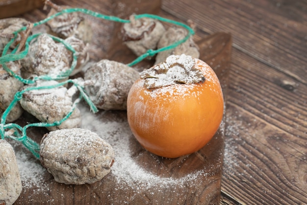 Delicious fresh and dried persimmon fruits on wooden board