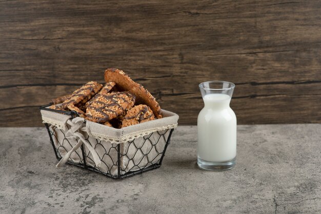 Delicious fresh multigrain cookies with chocolate glaze in basket with a glass jar of milk.