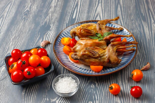 Free photo delicious fried quail with herbs and cherry tomatoes.