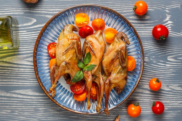 Free Photo delicious fried quail with herbs and cherry tomatoes.