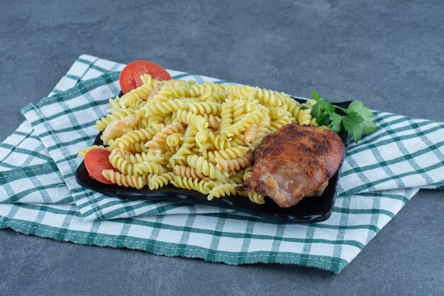 Delicious fusilli with chicken on dark plate. 