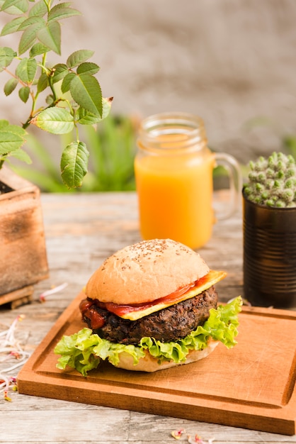 Delicious hamburger on chopping board served with juice jar on wooden desk