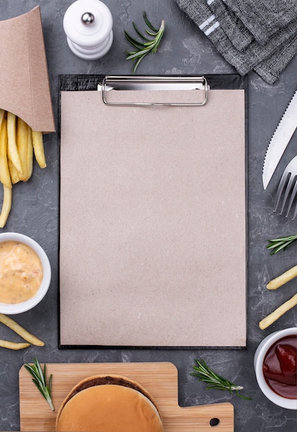 Free photo delicious hamburger and fries with clipboard beside