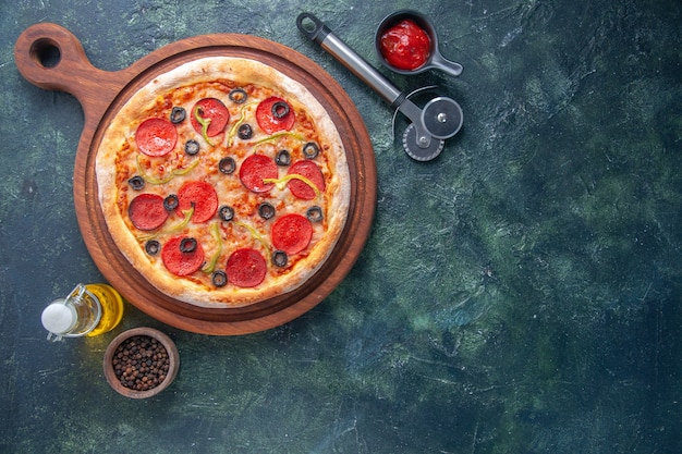 Delicious homemade pizza on wooden board tomatoes and oil bottle pepper ketchup on the right side on dark surface