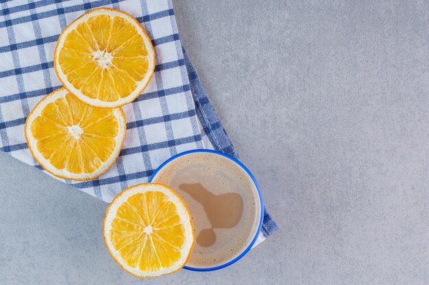 Delicious hot coffee and sliced oranges on stone table.