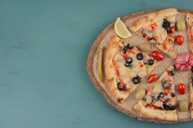 Delicious hot pizza with olives and tomatoes on blue surface. 