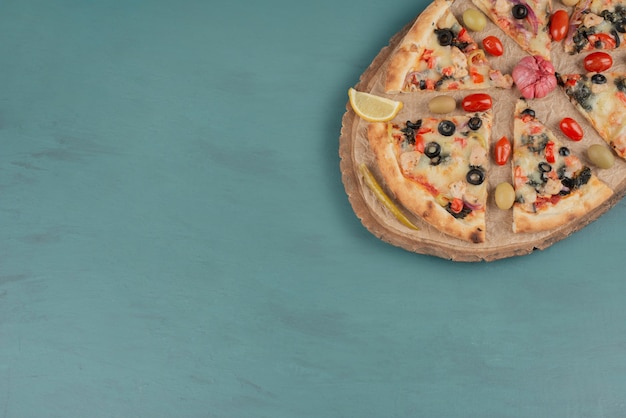 Delicious hot pizza with olives and tomatoes on blue surface. 