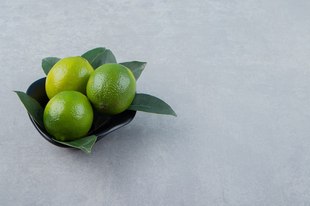 Delicious lime fruits in black bowl. 