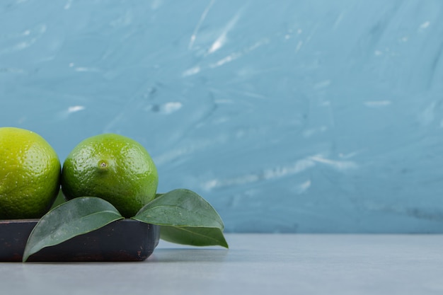 Free photo delicious lime fruits with leaves on black plate.