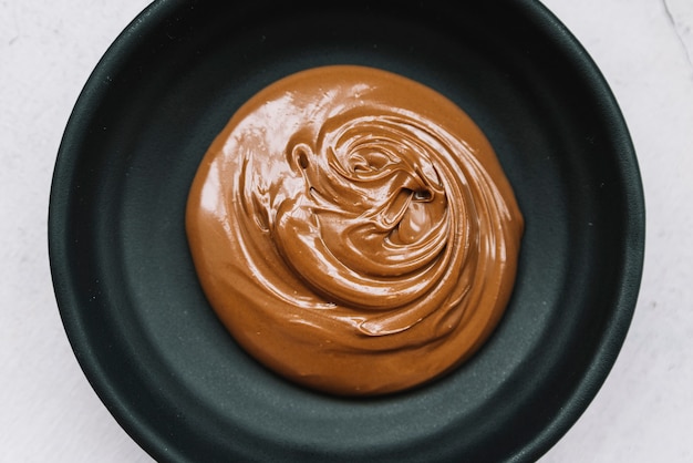 Delicious melted chocolate in black bowl over white background