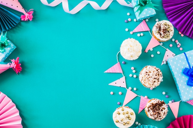 Delicious muffins with party accessories on green surface