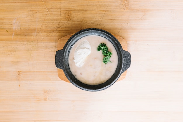 Free Photo delicious mushroom cream soup in container against wooden backdrop