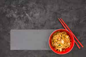 Free photo delicious noodles on black slate with chopsticks over textured background