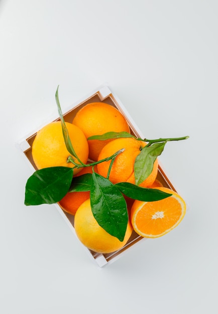 Delicious oranges in a wooden box with branch top view