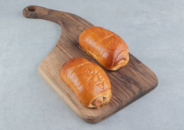 Delicious pastries with sausages on wooden board. 