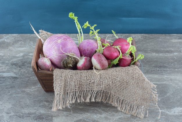 Free photo delicious radishes on towel in the box, on the marble table.