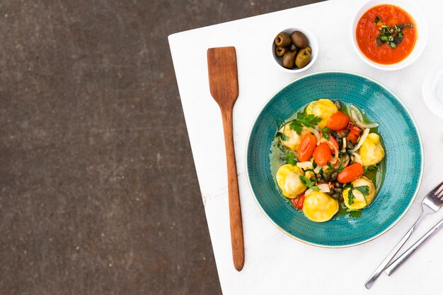 Delicious ravioli pasta with tomato sauce and olives on table