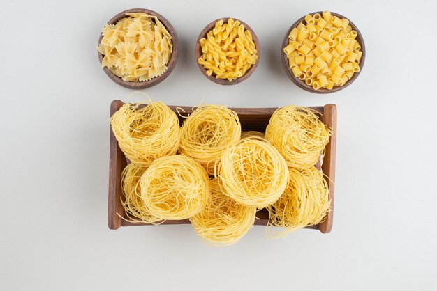 Delicious raw macaroni on wooden plate