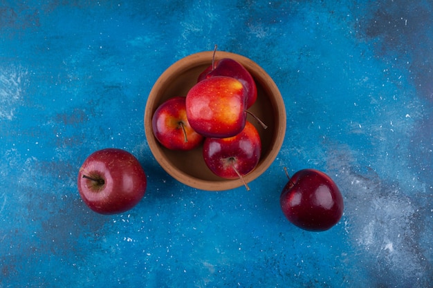 Free photo delicious red shiny apples placed on blue table.