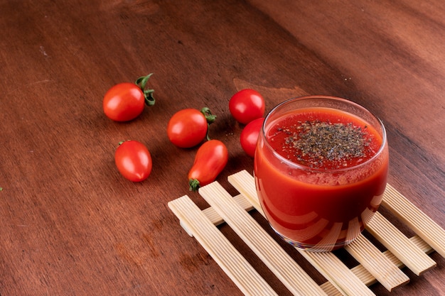 delicious red tomato juice in glass with black pepper on wooden table