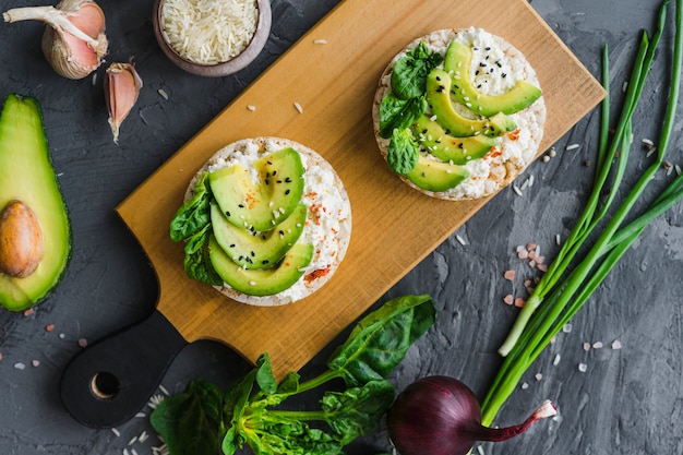 Free photo delicious rice cake with cream cheese and avocado over wooden board with organic vegetables