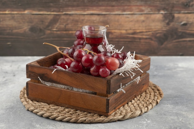 Delicious ripe grapes and glass of juice in wooden box. 