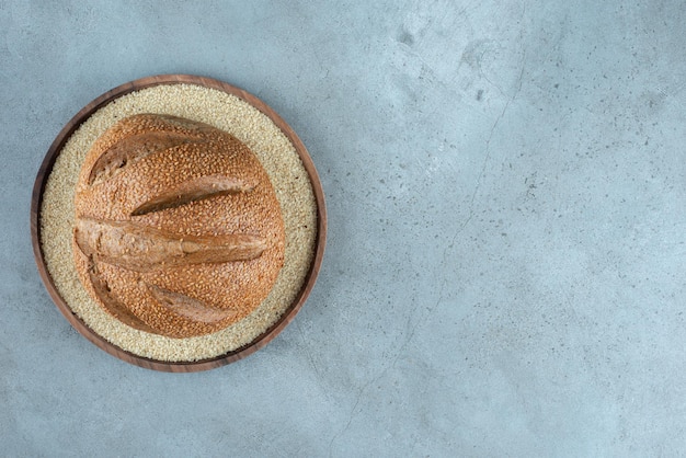 Delicious rye bun on wooden plate.