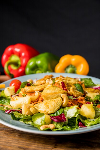 Delicious salad with chicken; nuts; and vegetables on desk against black background