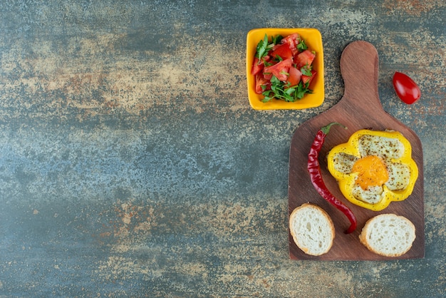 Delicious salad in yellow plate with fried omelet in pepper on marble background