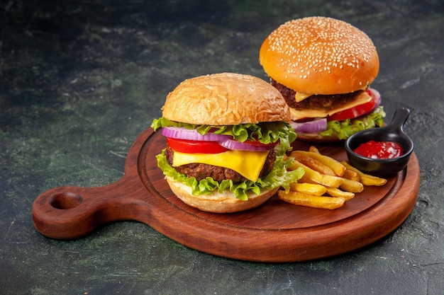 Delicious sandwiches fries ketchup on wooden cutting board on dark mix color surface