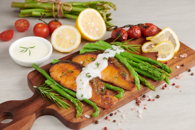 Free photo delicious seasonal green asparagus and sliced smoked salmon on rustic plate