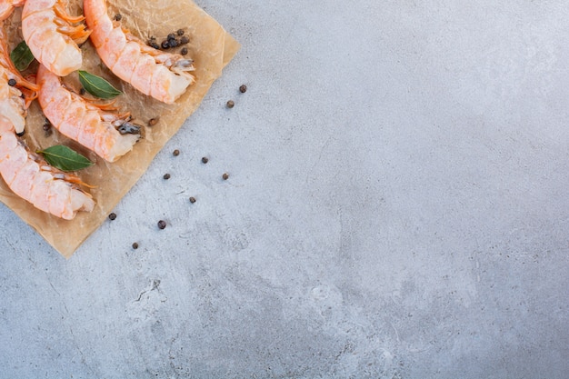 Delicious shrimps with sliced lemon and peppercorns on greaseproof paper 