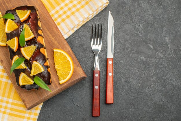 Delicious soft cakes on wooden board and cut lemons with leaves on green striped towel