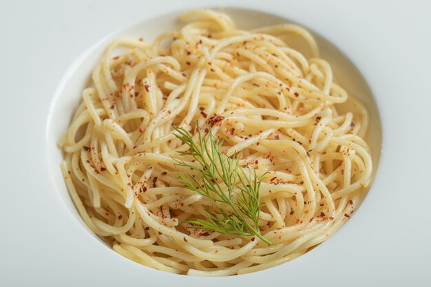 Delicious spaghetti with greens on a white plate.