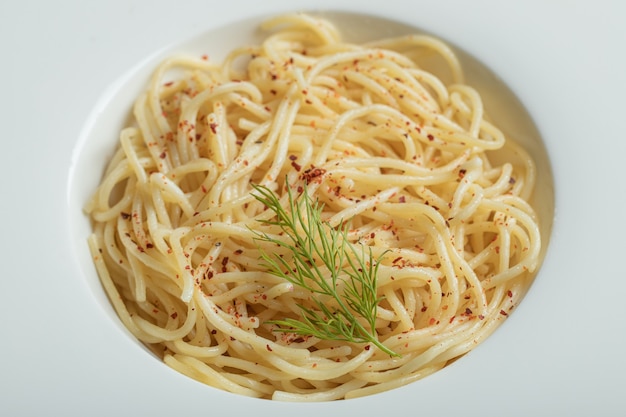 Delicious spaghetti with greens on a white plate.