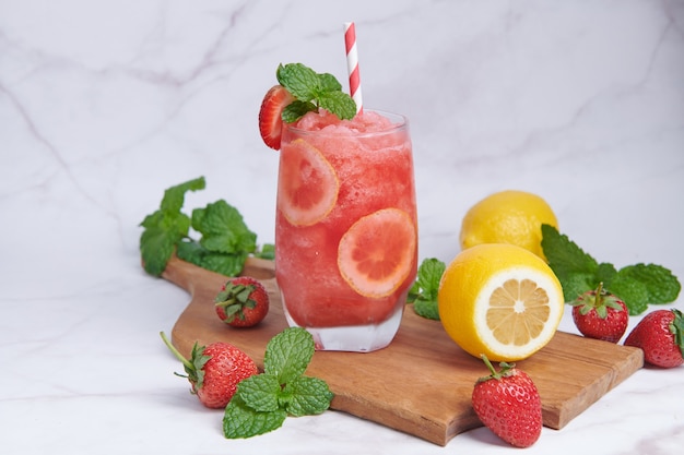 Delicious strawberry and lemon smoothie garnished with fresh strawberry and mint in glass. soft focus. beautiful appetizer pink strawberry, well being and weight loss concept.