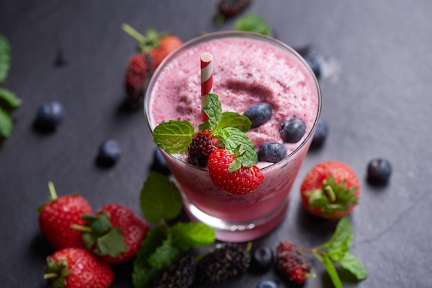 Delicious strawberry, mulberry and blueberry smoothie garnished with fresh berries and mint in glass. soft focus. beautiful appetizer pink raspberries, well being and weight loss concept.