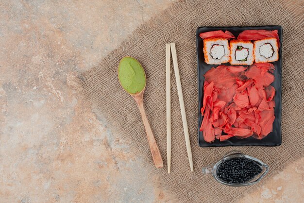 Delicious sushi with caviar, ginger and vasabi on wooden plate 