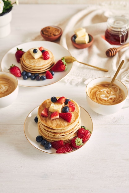 Delicious vegan pancakes with fruits on a white plate