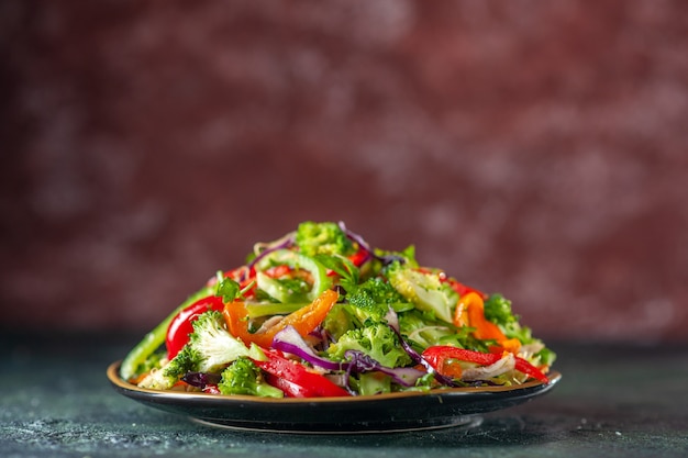 Delicious vegan salad with fresh ingredients in a plate on blue and maroon blurred background