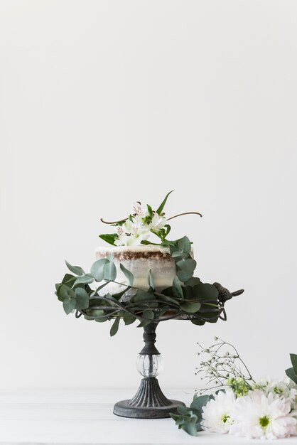 Delicious wedding cake decorated with flowers against white background