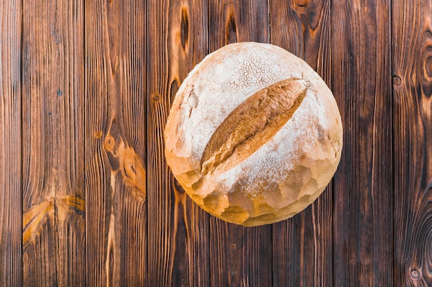 Delicious whole round bread on wooden background